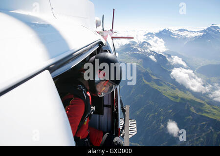 Femmina sky diver in elicottero il controllo per uscire sulla montagna, Interlaken, Berna, Svizzera Foto Stock