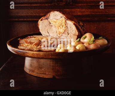 Arrosto di cosciotto di agnello disossato e farcito con patate di primizia in legno vintage portagiornali Foto Stock