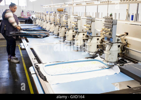 Femmina operaio di fabbrica la preparazione di panno per velocità programmata di cucitura della macchina da ricamo in fabbrica di abbigliamento Foto Stock