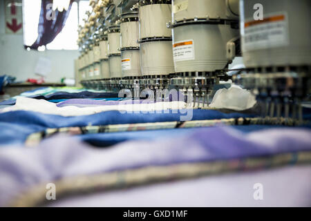 File di ricamo programmata velocità di macchine di cucitura panno blu nella fabbrica di abbigliamento Foto Stock