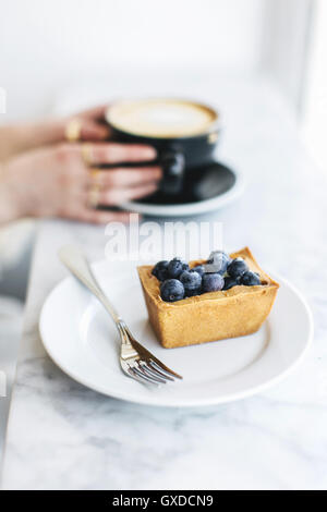 Crostata di frutta e di una donna mani di schiuma di caffè Foto Stock