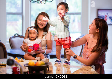 Baby boy in piedi e battendo le mani sul tavolo da pranzo Foto Stock