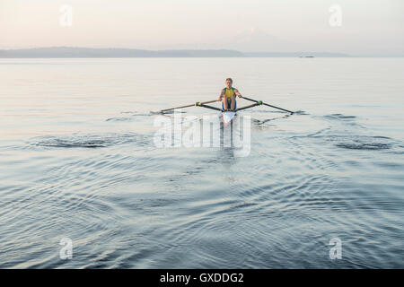 Uomo fila a remi in barca mare intorno Bainbridge Island, Washington, Stati Uniti d'America Foto Stock