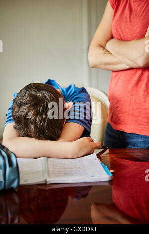Madre in piedi da sconvolgere figlio di fare i compiti di scuola Foto Stock