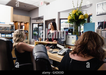 Receptionist frequentando il cliente nel salone di parrucchiere Foto Stock