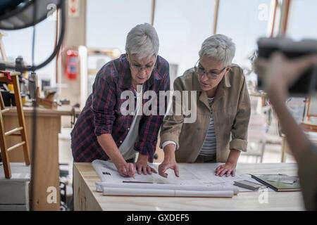 Falegnami femmina discutendo blueprint nella fabbricazione di mobili workshop Foto Stock