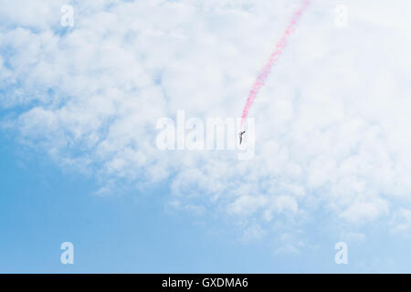 Formazione piano jet acrobazia nella vastità del cielo blu e nuvole bianche. Colore rosso trace dietro il velivolo. Spazio libero Foto Stock