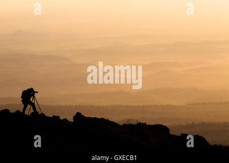 Silhouette di un fotografo che spara un tramonto in montagna durante il tramonto Foto Stock