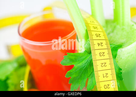 Nastro di misurazione, bicchiere di succo di sedano e un bicchiere di succo di carota Foto Stock