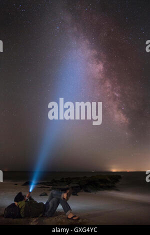 Uomo asiatico shining torcia elettrica sul cielo stellato Foto Stock