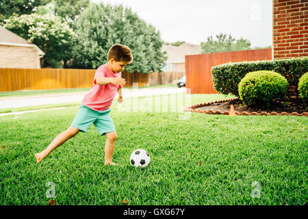 Ragazzo caucasico calci palla calcio sul prato Foto Stock