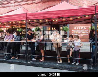 Adulti di rilassarsi con una birra mentre i ragazzi lo sciocco intorno a una strada attuale su Mulberry Street durante il San Gennaro festa in Little Italy, New York City Foto Stock