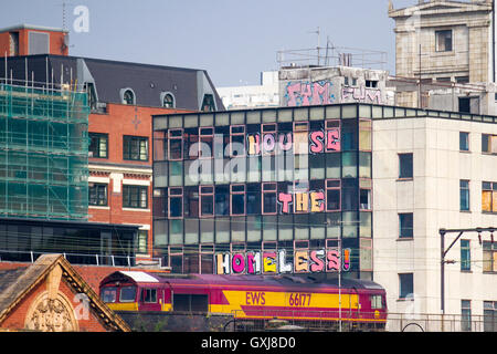 Casa ai senza tetto. Scritte poste nelle finestre delle proprietà non occupato. Lo skyline di edifici commerciali a Manchester, Regno Unito Foto Stock