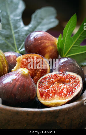 Fresche e mature fichi nero e foglie di fico nel recipiente rustico Foto Stock