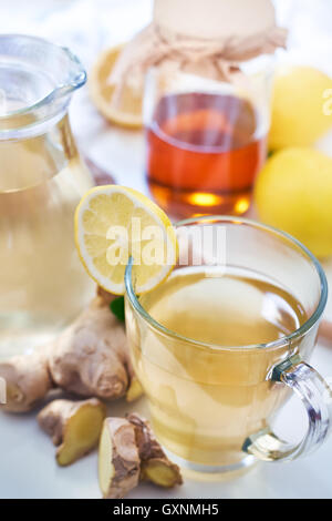 Il tè allo zenzero servito con miele e limone e menta sulla tavola bianco Foto Stock