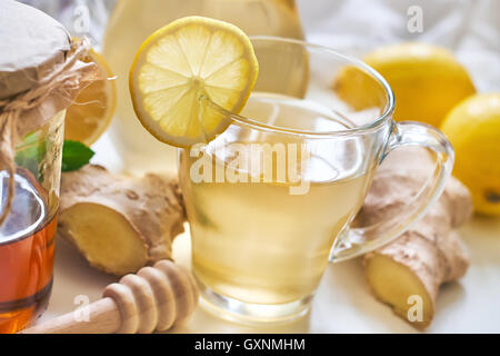 Il tè allo zenzero servito con miele e limone e menta sulla tavola bianco Foto Stock