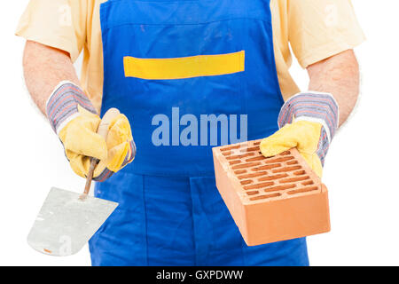 Lavoratore edile con un mattone e cazzuola in mani isolati su sfondo bianco. Immagine con un tracciato di ritaglio. Foto Stock