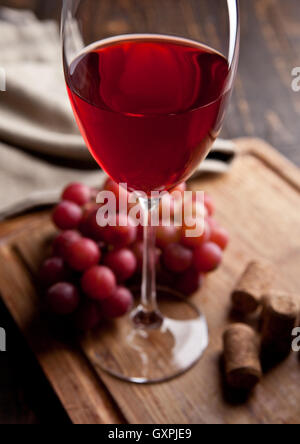 Bicchiere di vino rosso e uva sulla tavola di legno e sughero. Ottimo per bar e ristorante. Still Life Foto Stock