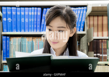 Asian studente di scuola superiore lettura in biblioteca presso il college. Uno asiatico studente di scuola superiore. Foto Stock