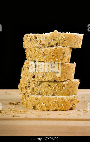 Fette di granaio baguette sul tagliere, contro uno sfondo nero Foto Stock