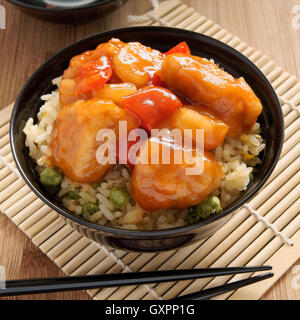 Dolce e aspro di pollo stile Cantonese con uovo fritto il riso in un recipiente di vernice con bacchette Foto Stock