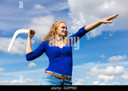 Giovane donna olandese gettando boomerang con cielo blu Foto Stock