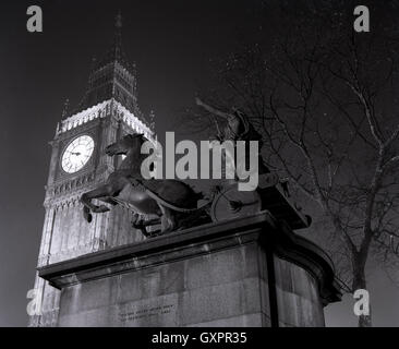 Degli anni Cinquanta, storico, la sera e la statua di Boadicea e le sue figlie è illuminato dalle luci di Londra famosa torre dell orologio (Big Ben). Foto Stock