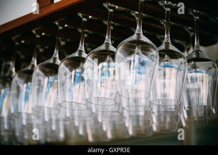 Occhiali appesi sopra bar rack. Svuotare i bicchieri per il vino al di sopra di una barra a cremagliera Foto Stock