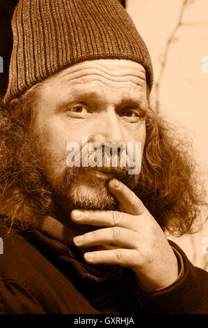Testa e la spalla ritratto di un uomo anziano con la barba folta e cappello di lana monocromatico. Foto Stock