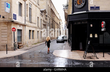 Donna di pulizia fuori strada il suo ristorante a Bordeaux Foto Stock