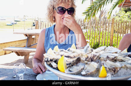 Donna di mangiare in una spiaggia di ostriche e di molluschi bar e ristorante in Cap Ferret sulla costa atlantica della Francia Foto Stock