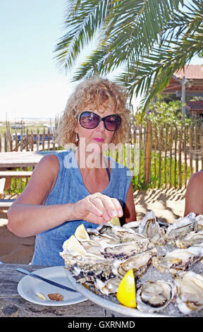 Donna di mangiare in una spiaggia di ostriche e di molluschi bar e ristorante in Cap Ferret sulla costa atlantica della Francia Foto Stock
