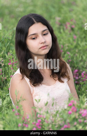 Ragazza seduta sul prato con fiori Foto Stock