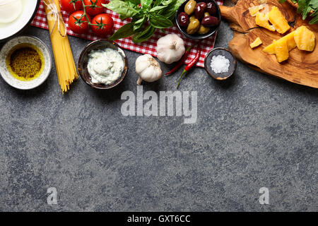 Il cibo italiano ingredienti sfondo con materie spaghetti, olive, foglie di basilico e parmigiano, mozzarella, ricotta, aglio, chil Foto Stock
