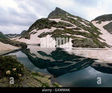 Immagine speculare dei picchi di montagna sono coperti con ghiacciai nel lago Foto Stock