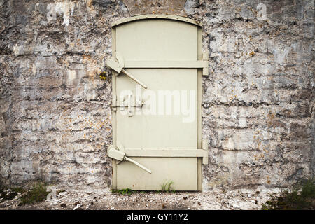 Bloccato massiccia porta di metallo nelle vecchie mura di fortificazione, texture di sfondo Foto Stock