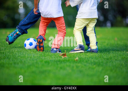 Padre e figli a giocare a calcio in posizione di parcheggio Foto Stock