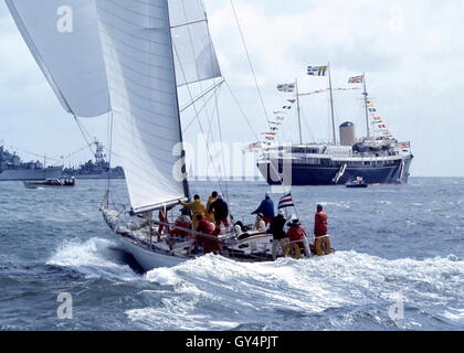 AJAX NEWS FOTO. 1971. SOLENT, Inghilterra. - ADMIRAL'S CUP - AMERICAN ENTRATA YANKEE GIRL poteri verso COWES strade con il Royal Yacht Britannia HMRY E GUARDSHIPS NAVALE IN BACKGROUND. Foto:JONATHAN EASTLAND/AJAX REF:C7105D6 3 Foto Stock