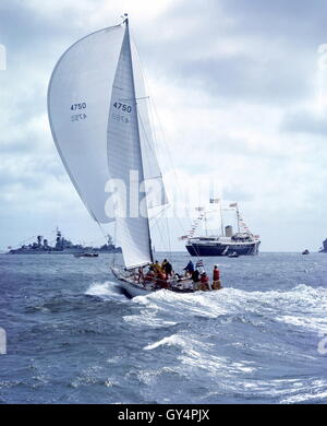 AJAX NEWS FOTO. 1971. SOLENT, Inghilterra. - ADMIRAL'S CUP - AMERICAN ENTRATA YANKEE GIRL poteri verso COWES strade con il Royal Yacht Britannia HMRY E GUARDSHIPS NAVALE IN BACKGROUND. Foto:JONATHAN EASTLAND/AJAX REF:C7105D6 Foto Stock