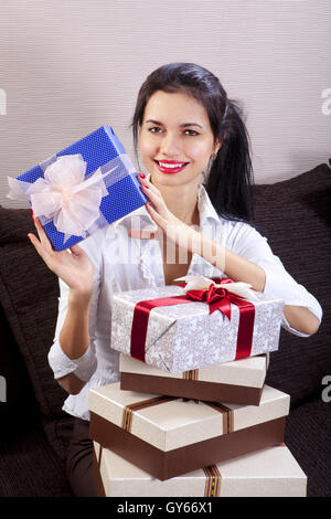 Giovane donna felice sorridente e trattiene confezione regalo in mani Foto Stock