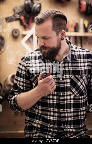 Ritratto di un uomo di fumare tubo in officina in legno Foto Stock