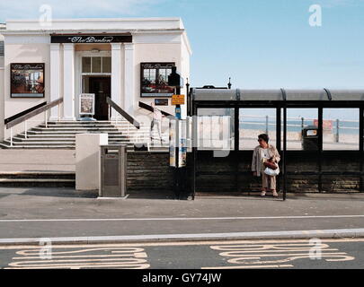 AJAXNETPHOTO. WORTHING, Inghilterra. - Al Mare - UNA DONNA attende un autobus mentre un guidatore di skateboard in sottofondo sul lungomare. Foto:JONATHAN EASTLAND/AJAX REF:0222 24 21A Foto Stock