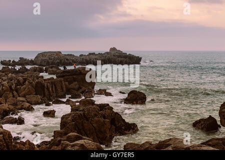 Due pescatori con le loro aste on the rocks, il fondo del mare, costiera nel nord della Cantabria, SPAGNA Foto Stock