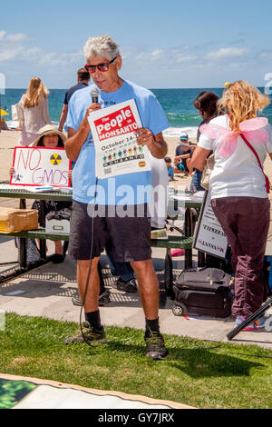 Un anziano gli indirizzi degli altoparlanti attivisti condannare geneticamente modificati prodotti agricoli (OGM) durante una dimostrazione presso la spiaggia principale in Laguna Beach, CA. Nota ali di farfalla a destra. Foto Stock