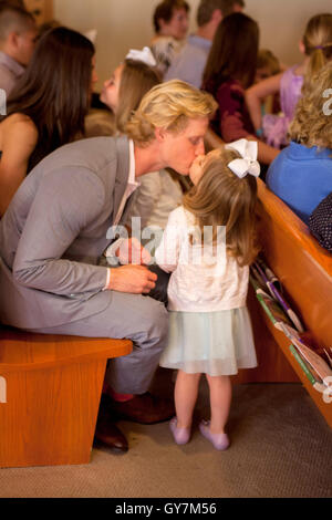 Una bambina bacia il padre affettuosamente in un pew durante i servizi ad una Laguna Niguel, CA, chiesa. Foto Stock
