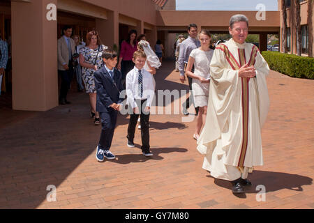 Un derubato monsignor conduce un orgoglioso processione di formalmente vestiti multirazziale teens e tweens fuori di una Laguna Niguel, CA, chiesa cattolica a conclusione della loro prima Comunione mass. La prima comunione è una cerimonia in alcune tradizioni cristiane durante whic Foto Stock