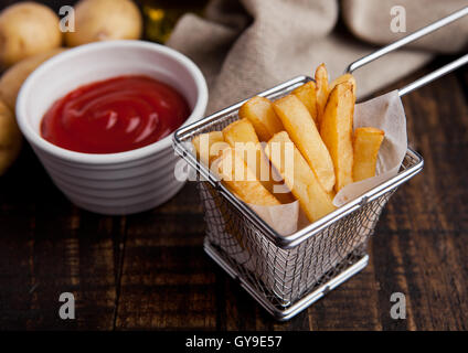 Frittura di patatine fritte chip nella friggitrice con ketchup su legno Foto Stock