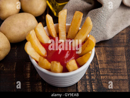 Frittura di patatine fritte chip nella friggitrice con ketchup sul legno. Il cibo spazzatura Foto Stock