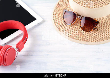 Occhiali da sole con red headphones, tablet e un cappello. Concetto di viaggio. Foto Stock