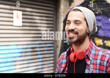 Ritratto di giovane uomo latino con red headphones. Scena urbana. Foto Stock